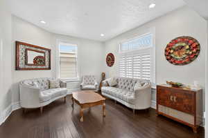 Living room featuring dark wood finished floors, a textured ceiling, and recessed lighting