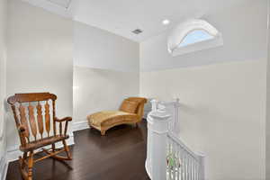 Sitting room with vaulted ceiling, an upstairs landing, and dark wood-style floors