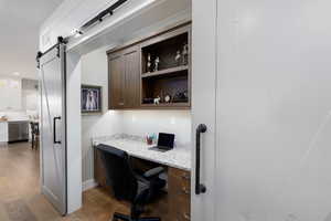 Office area featuring built in study area, light wood-type flooring, and a barn door.