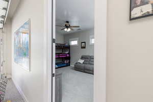 Hallway featuring light colored carpet and a textured ceiling