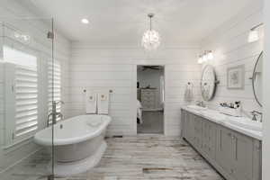 Bathroom with a freestanding bath, double vanity, ensuite bathroom, a chandelier, and recessed lighting