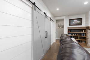 Hallway with a barn door, dark wood finished floors, and recessed lighting