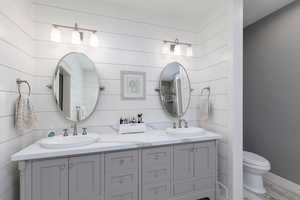 Full bathroom featuring double vanity and toilet