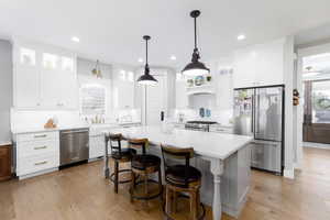 Kitchen featuring high quality appliances, backsplash, light wood-type flooring, a kitchen bar, and a kitchen island.