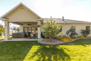 Back of property featuring a hot tub, ceiling fan, a patio, and roof with shingles.