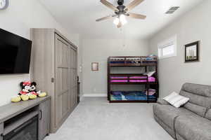 Bedroom featuring light colored carpet and a ceiling fan.