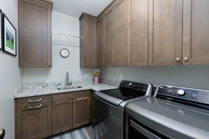 Washroom featuring washer and clothes dryer, cabinet space, and a textured ceiling, pull out garbage and ironing board.