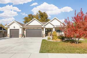 Craftsman house with board and batten siding, an attached two-car garage, stone siding, concrete driveway, and a front lawn.