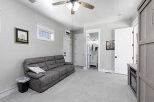 Living area with light colored carpet and a ceiling fan