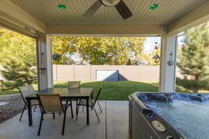 Fenced backyard with a patio, ceiling fan, outdoor dining space, and a hot tub.