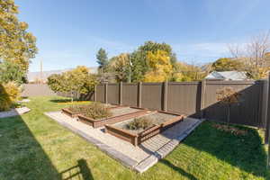 Fenced backyard featuring a garden, with three large metal planters.