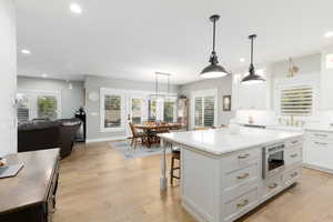Kitchen with recessed lighting, a breakfast bar, pendant lighting, a center island, and light wood-style floors.
