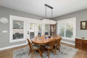 Dining area with plenty of natural light, light wood finished floors, and a chandelier.