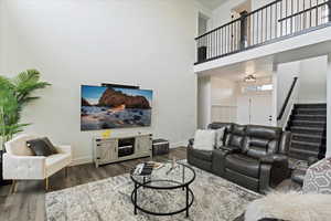 Living area with a high ceiling, stairway, and wood finished floors