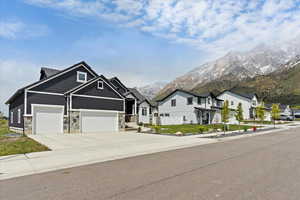 Craftsman-style home with stone siding, board and batten siding, driveway, a mountain view, and a residential view