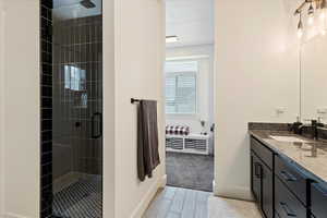 Ensuite bathroom featuring vanity, a stall shower, and wood tiled floors