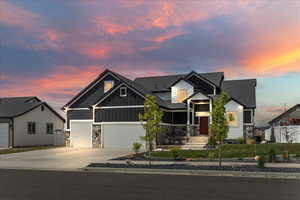 Craftsman house with board and batten siding, driveway, a garage, stone siding, and a shingled roof