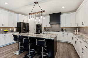 Kitchen with light stone countertops, white cabinets, pendant lighting, tasteful backsplash, and recessed lighting