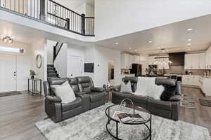 Living room featuring stairway, light wood-style flooring, a high ceiling, recessed lighting, and washer / clothes dryer