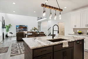 Kitchen with dark wood finished floors, light stone countertops, recessed lighting, white cabinets, and decorative light fixtures