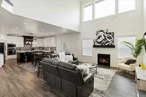 Living area featuring dark wood-style flooring, a fireplace, a high ceiling, and recessed lighting