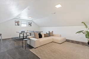 Living room with dark carpet, vaulted ceiling, and a textured ceiling