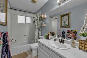 Full bath with shower / bathtub combination with curtain, vanity, and light tile patterned floors