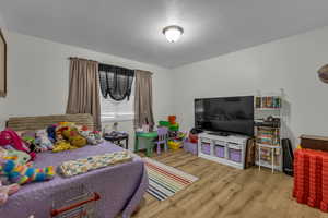 Bedroom with wood finished floors and a textured ceiling