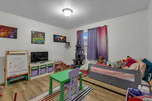 Bedroom with wood finished floors and a textured ceiling