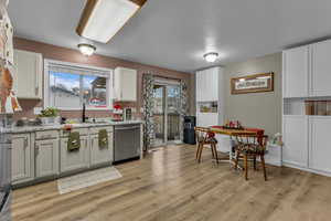 Kitchen with appliances with stainless steel finishes, white cabinetry, healthy amount of natural light, and light wood finished floors