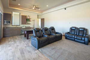 Living room featuring a raised ceiling, ceiling fan, recessed lighting, and light wood-style floors