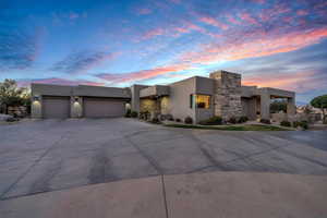 Modern home featuring stucco siding, concrete driveway, an attached garage, and stone siding