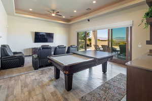 Playroom with light wood finished floors, a raised ceiling, pool table, and recessed lighting