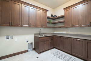 Laundry room with electric dryer hookup, cabinet space, light tile patterned floors, and washer hookup