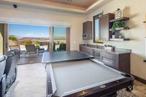 Game room featuring wine cooler, healthy amount of natural light, bar, and a raised ceiling