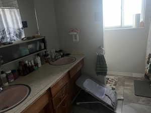 Full bath featuring double vanity, a shower with shower curtain, and light tile patterned floors