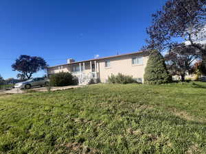 Back of house featuring a lawn, a chimney, and an attached garage
