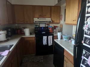 Kitchen featuring black appliances, tasteful backsplash, extractor fan, and light countertops