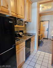 Kitchen with black appliances, light tile patterned floors, light brown cabinetry, and light carpet