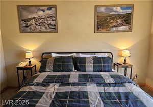 Carpeted bedroom featuring baseboards and a textured wall