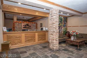 Reception featuring decorative columns, bar with sink, beam ceiling, and crown molding