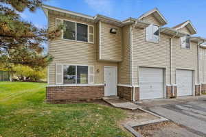 View of front of home with brick siding, driveway, a front yard, and a garage