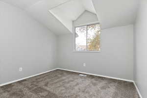 Additional living space featuring vaulted ceiling and carpet