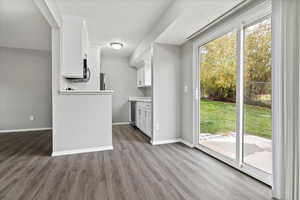 Kitchen with light wood-style flooring, light countertops, white cabinets, and stainless steel dishwasher