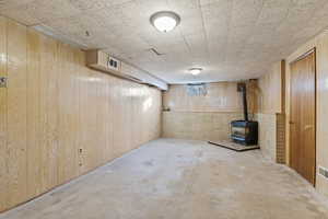 Below grade area featuring a wood stove and wooden walls