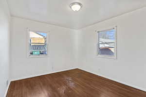 Unfurnished room with dark wood-style floors and baseboards