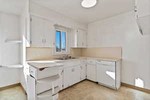 Kitchen featuring light countertops, dishwasher, and white cabinetry