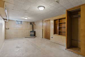 Below grade area featuring built in shelves, wooden walls, and a wood stove