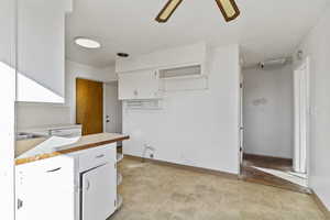 Kitchen with open shelves, light countertops, white cabinetry, light floors, and ceiling fan