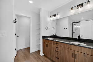 Full bath featuring a shower stall, recessed lighting, double vanity, and dark wood-type flooring